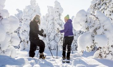 Sliding snowshoe trip in Rovaniemi couple enjoying the snowy winter nature of Finnish Lapland
